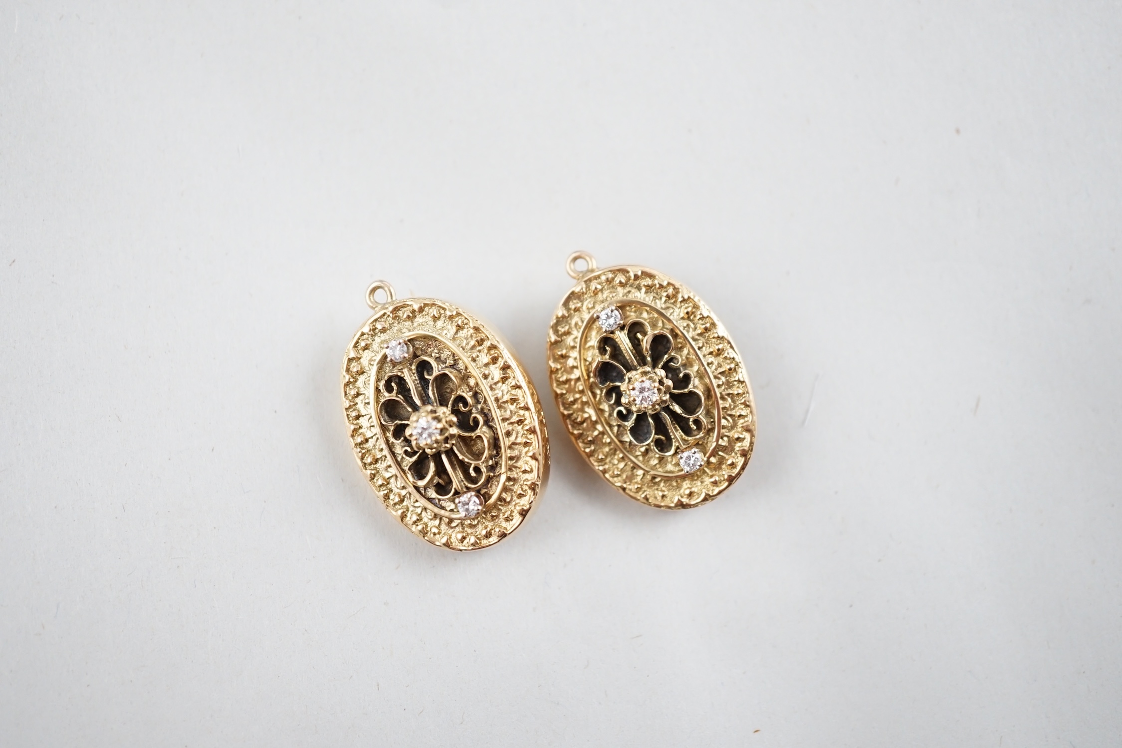 A modern pair of 9ct gold and three stone diamond set oval pendant brooches